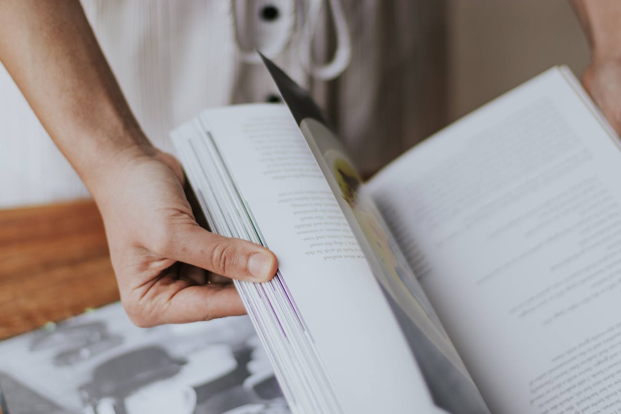 Person flipping through a book, showcasing focus and engagement with reading.